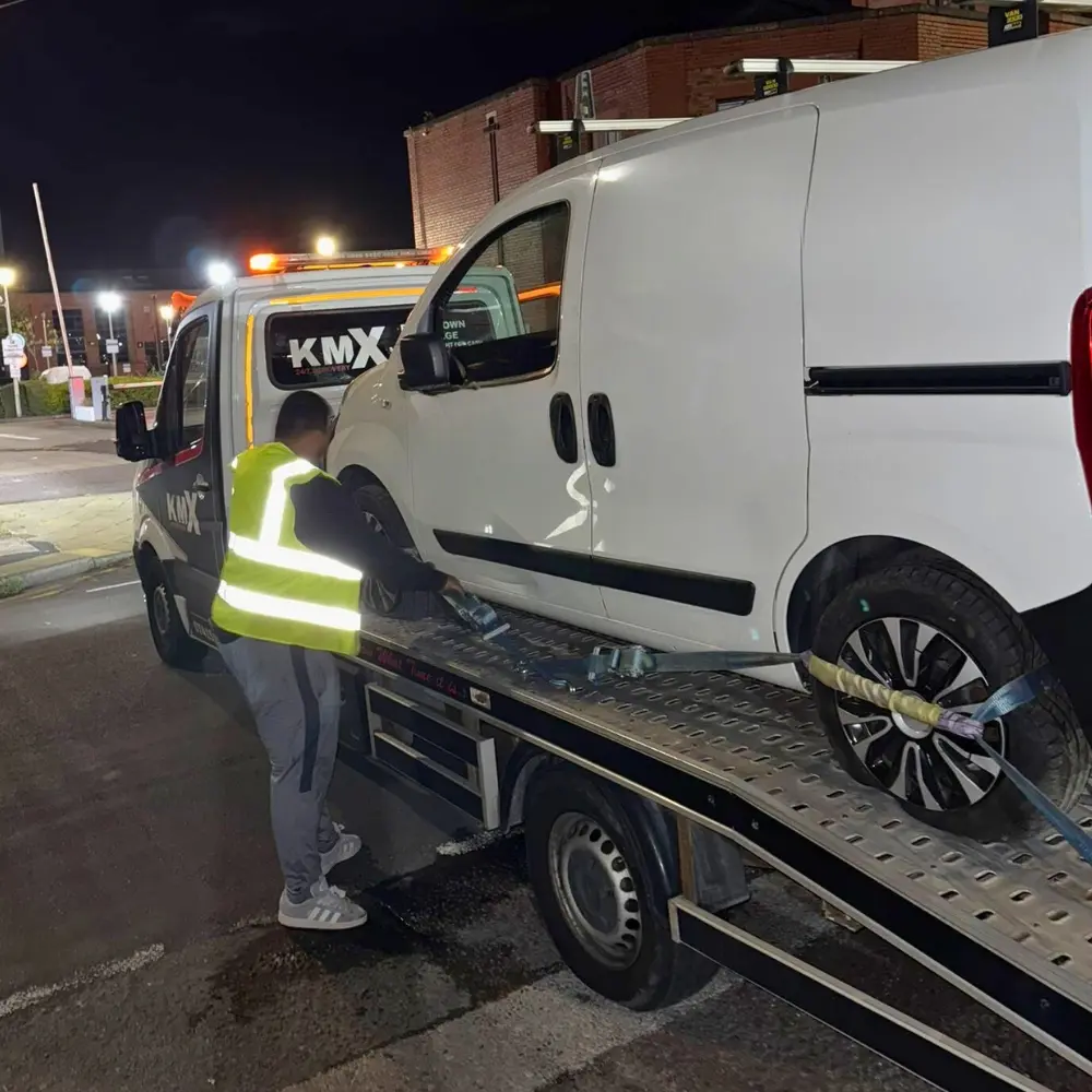 A KMX Recovery vehicle in action, lifting a broken-down van, alongside a team member carrying out his work.