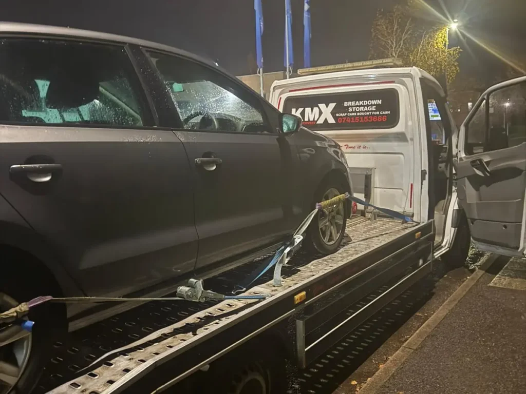 KMX Recovery loading a broken-down car onto a recovery truck at night in Bolton.