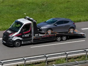 KMX recovery truck transporting a broken-down car as part of a 24/7 vehicle recovery service.