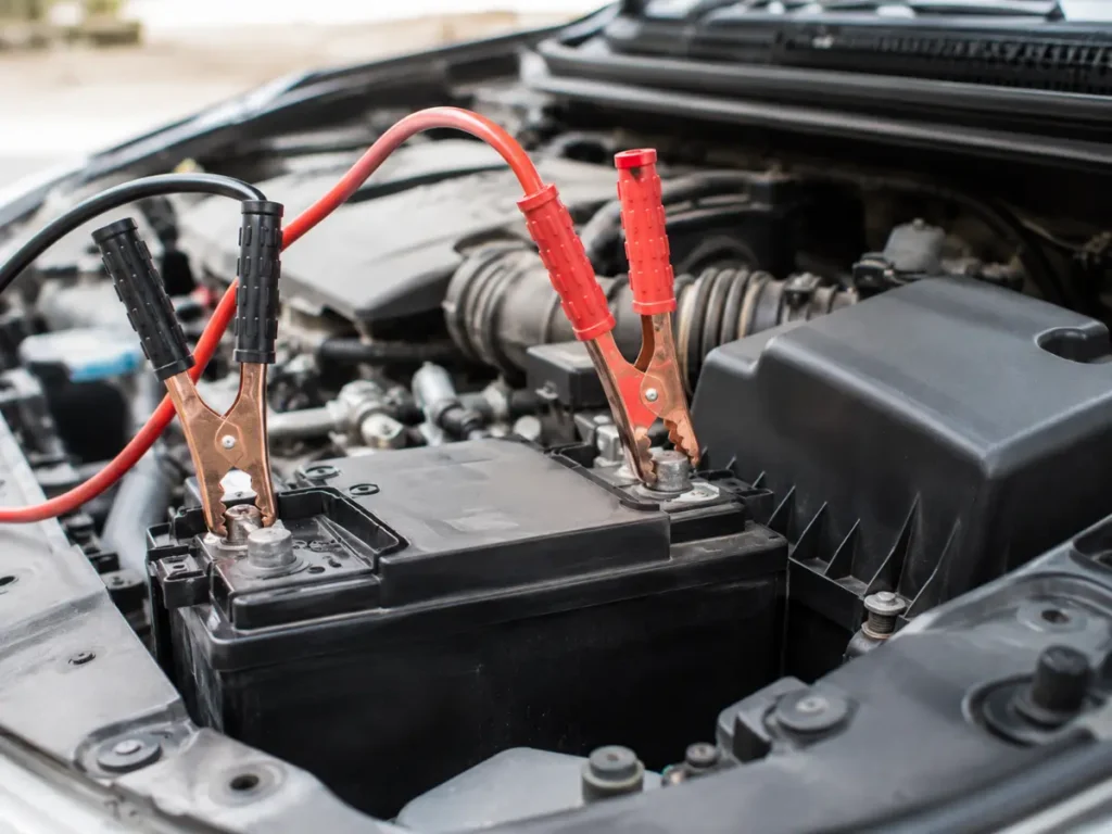 Close up of red and black jump leads connected to a car battery during a safe jump start.